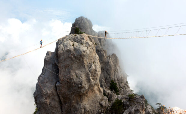 conversion optimization chasm illustrated by men walking a tightrope bridge on a mountain
