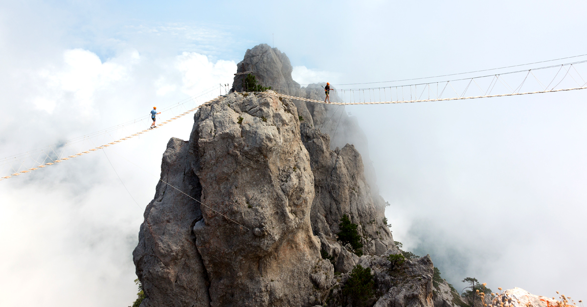 conversion optimization chasm illustrated by men walking a tightrope bridge on a mountain
